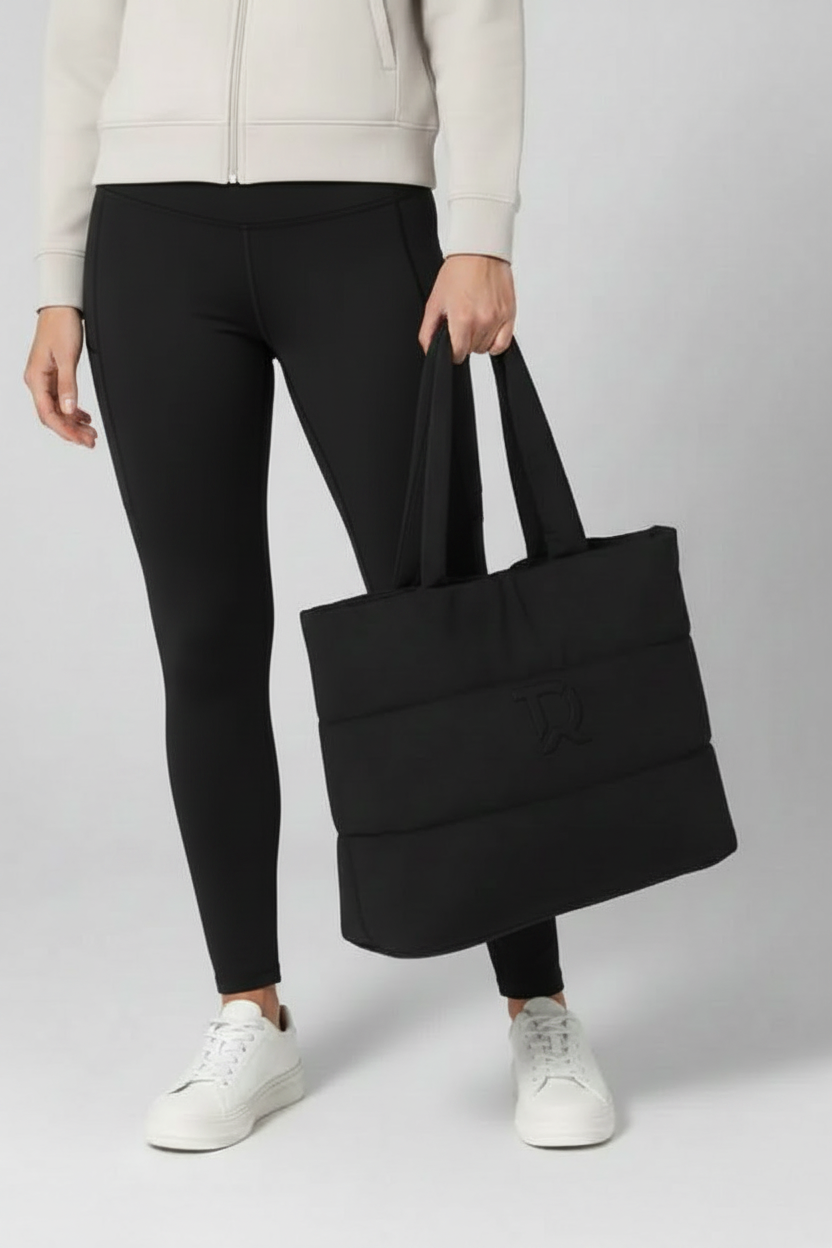 Donna con leggings neri a vita alta e tote bag con logo